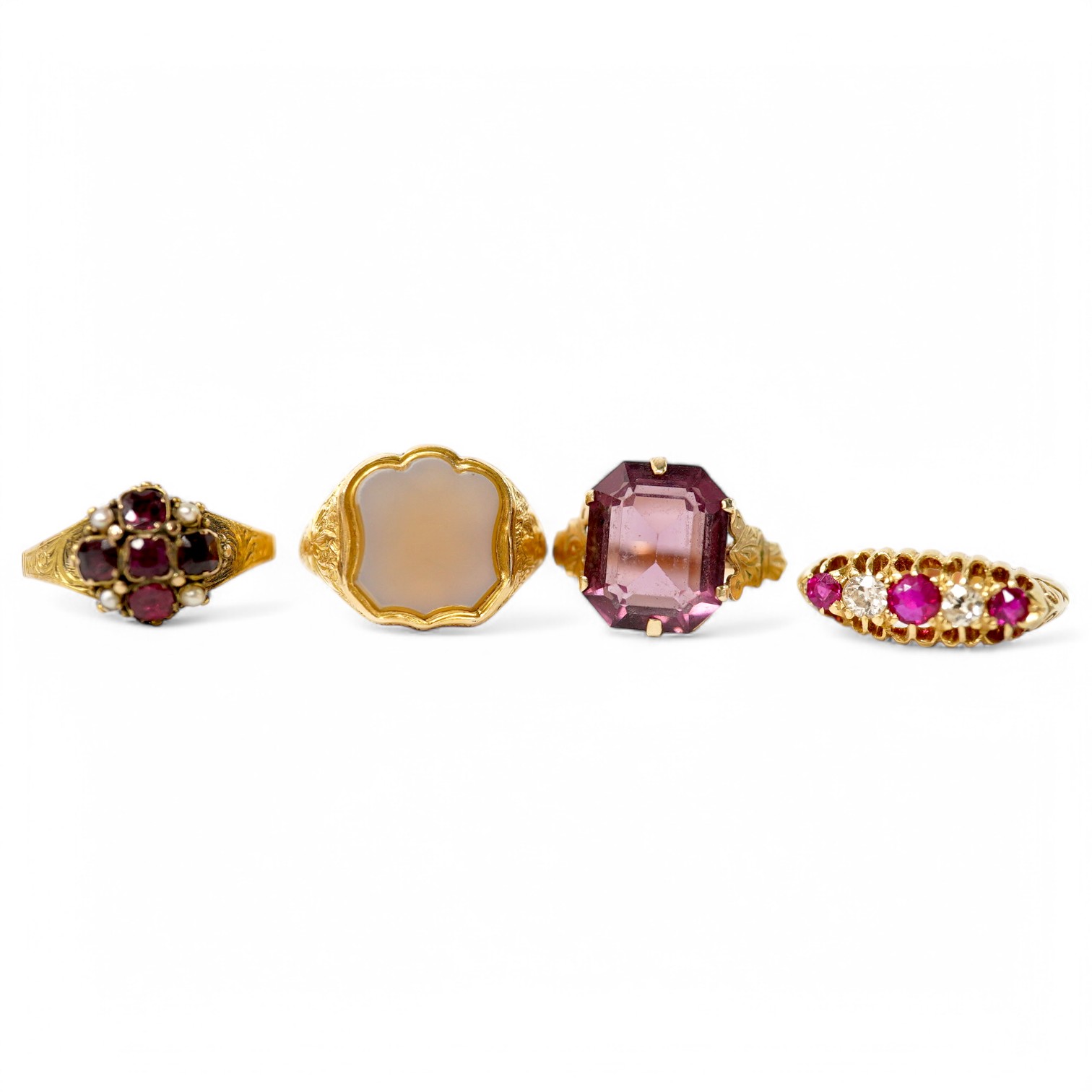 A group of four rings, comprising: a chalcedony signet ring with engraved floral shoulders, size L, partial British hallmarks for 15ct gold; a synthetic ruby and diamond five-stone ring, size N, stamped 18CT; a ring set